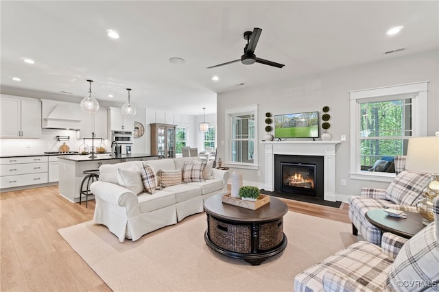 living room with light wood finished floors, visible vents, and recessed lighting