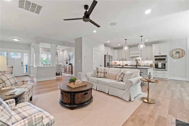 living room with visible vents, baseboards, ceiling fan, light wood-type flooring, and recessed lighting