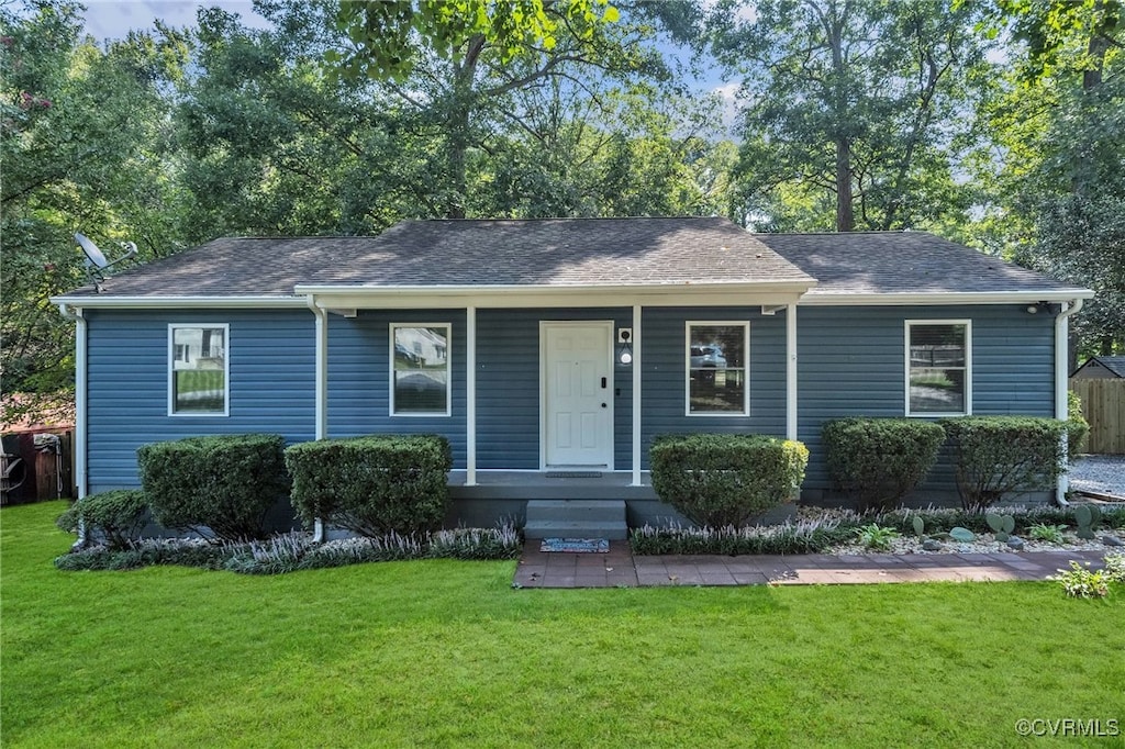 ranch-style home featuring covered porch and a front yard