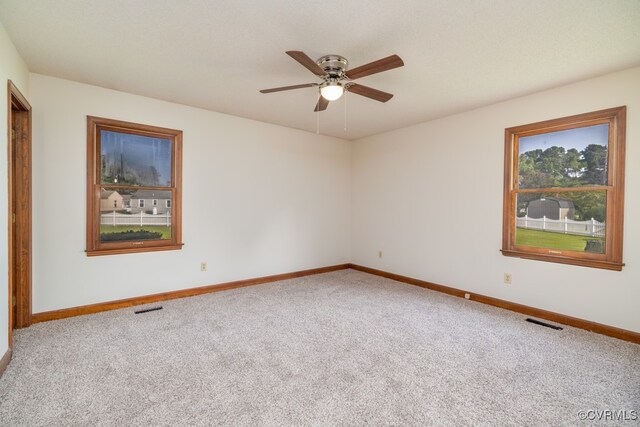 carpeted empty room with a healthy amount of sunlight and ceiling fan