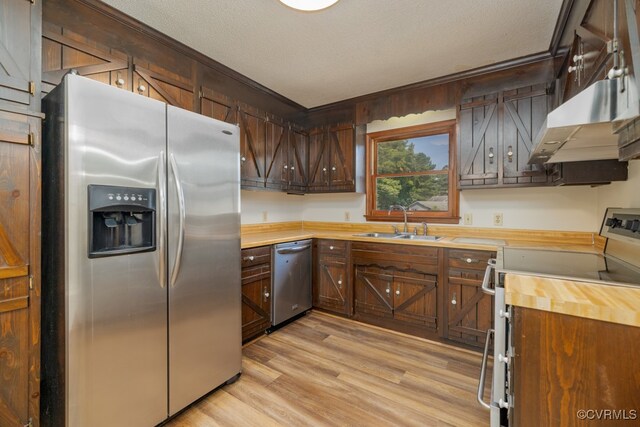 kitchen featuring a textured ceiling, appliances with stainless steel finishes, sink, ornamental molding, and light wood-type flooring