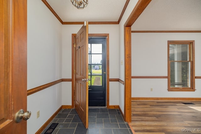 foyer entrance featuring dark wood-type flooring, ornamental molding, and a textured ceiling