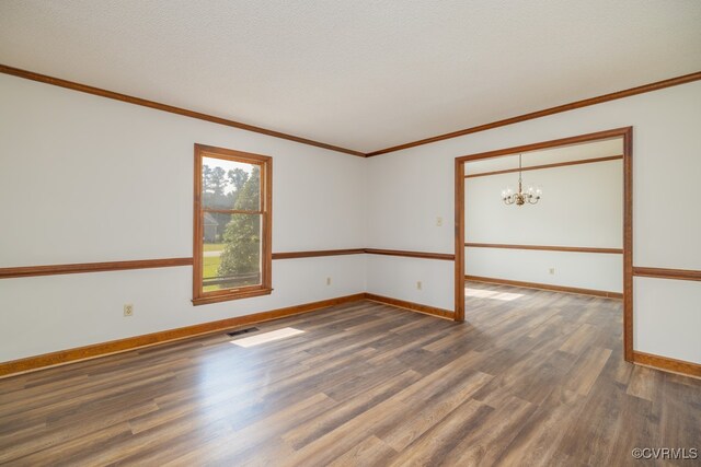 spare room with dark hardwood / wood-style floors, a chandelier, ornamental molding, and a textured ceiling