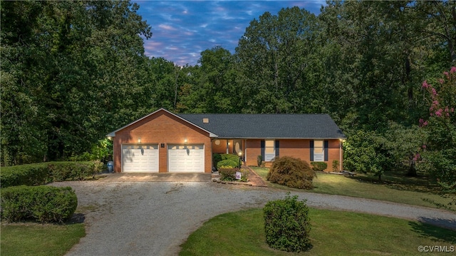 ranch-style home featuring a garage and a lawn