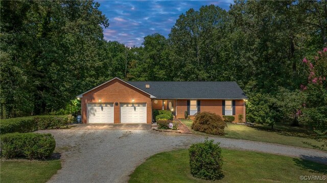 ranch-style house featuring gravel driveway, an attached garage, a front yard, and brick siding