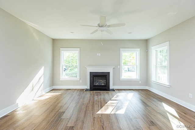 unfurnished living room featuring ceiling fan, wood-type flooring, and a fireplace