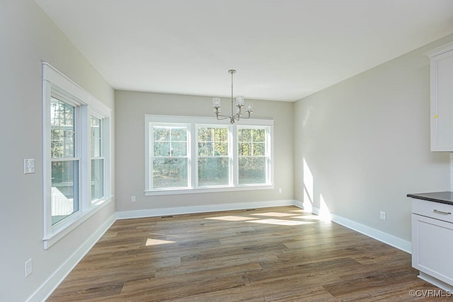 unfurnished dining area with dark hardwood / wood-style flooring and a chandelier