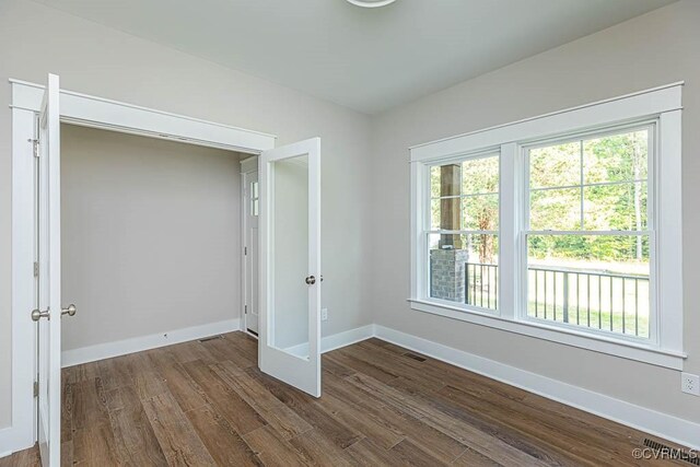 unfurnished bedroom with dark hardwood / wood-style floors and multiple windows