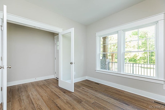 unfurnished bedroom featuring multiple windows and dark hardwood / wood-style flooring