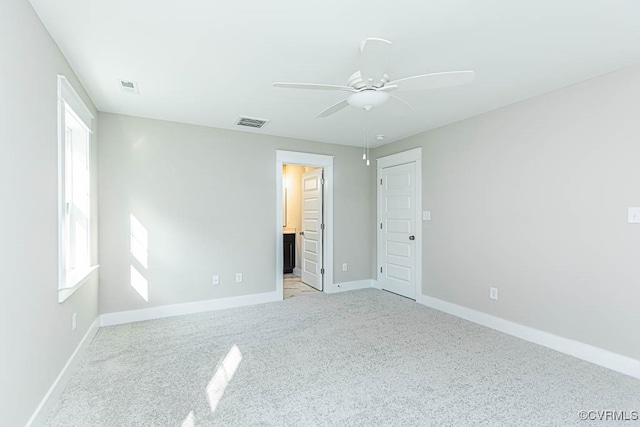 unfurnished bedroom with light colored carpet, ensuite bath, and ceiling fan