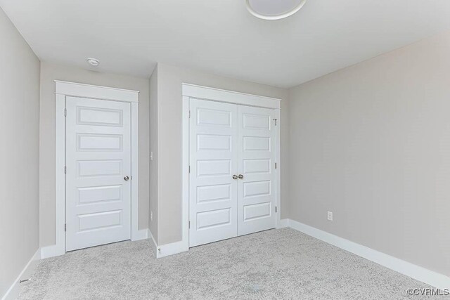 unfurnished bedroom featuring light colored carpet and a closet