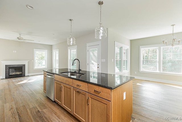 kitchen with ceiling fan with notable chandelier, a center island with sink, sink, stainless steel dishwasher, and light hardwood / wood-style floors