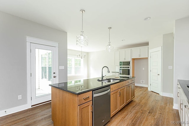 kitchen featuring a kitchen island with sink, a notable chandelier, stainless steel appliances, sink, and hardwood / wood-style flooring