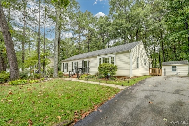 ranch-style home featuring an outbuilding, driveway, a front lawn, and entry steps