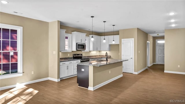 kitchen with appliances with stainless steel finishes, a center island with sink, white cabinetry, and sink