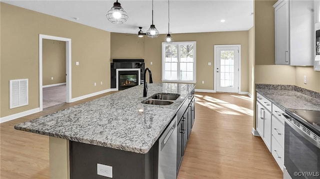 3323 Rock Creek Villa Dr, Quinton, VA 23141 - kitchen featuring visible vents, a ceiling fan, a sink, a glass covered fireplace, and appliances with stainless steel finishes