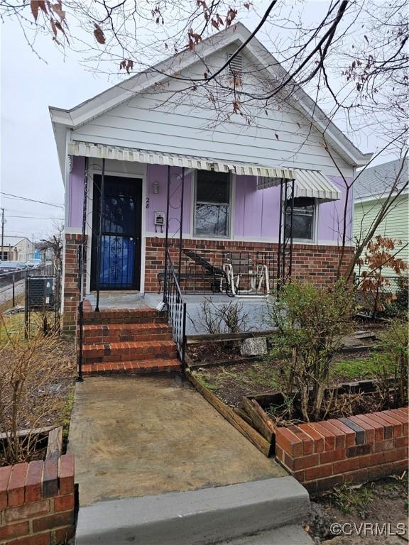 view of front facade with brick siding and covered porch