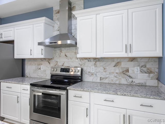 kitchen with wall chimney exhaust hood, light stone countertops, stainless steel appliances, and white cabinets