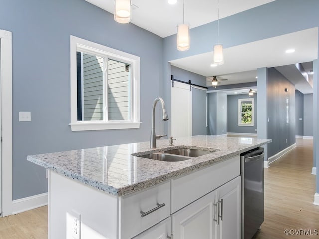 kitchen featuring a kitchen island with sink, pendant lighting, sink, stainless steel dishwasher, and a barn door