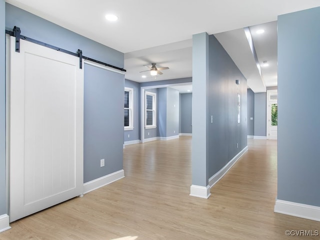 hallway with a barn door and light hardwood / wood-style floors