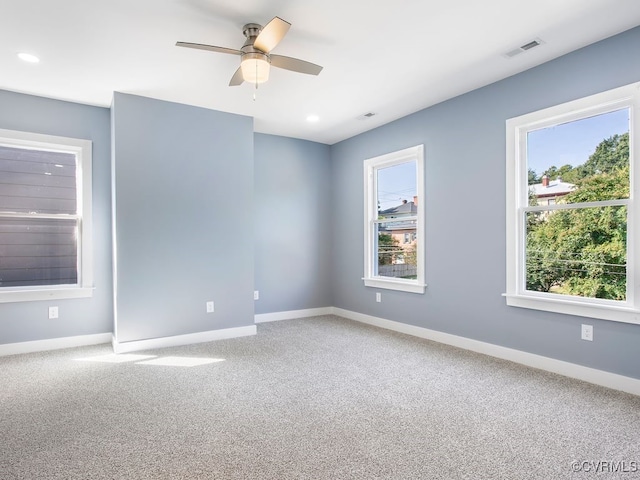 empty room featuring carpet flooring, ceiling fan, and a wealth of natural light