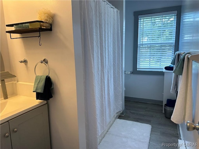 full bath featuring curtained shower, baseboards, wood finished floors, and vanity