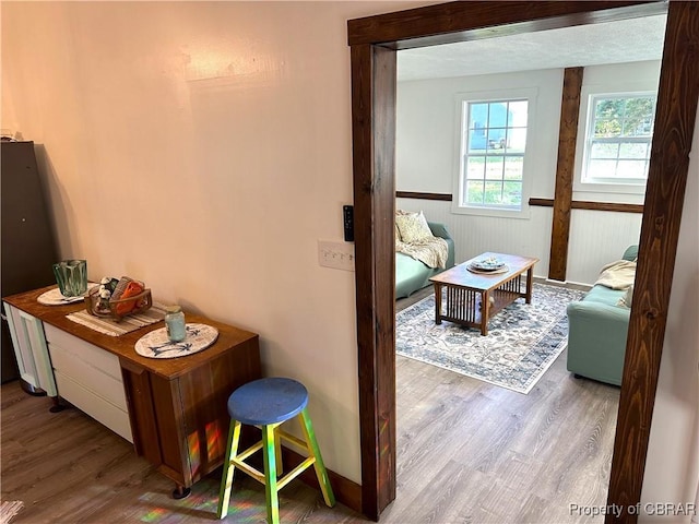 hallway featuring a wainscoted wall, a textured ceiling, and wood finished floors