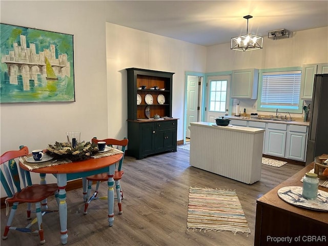 kitchen featuring dark wood-type flooring, a sink, fridge, light countertops, and a chandelier