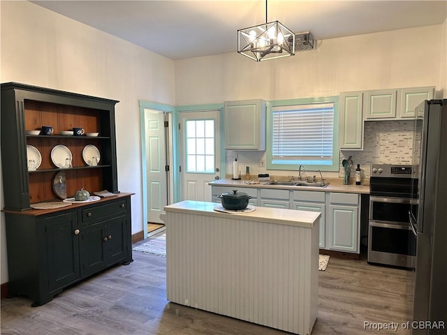 kitchen featuring a sink, wood finished floors, freestanding refrigerator, and range with two ovens