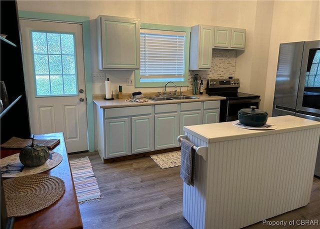 kitchen featuring light countertops, decorative backsplash, dark wood-style floors, stainless steel appliances, and a sink