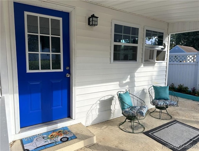 view of exterior entry featuring cooling unit and fence