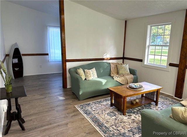 living area featuring a wainscoted wall, a textured ceiling, and wood finished floors