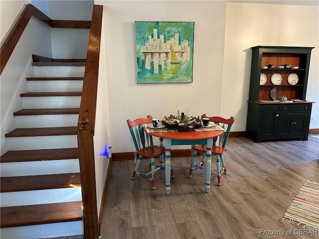 dining room featuring baseboards, wood finished floors, and stairs