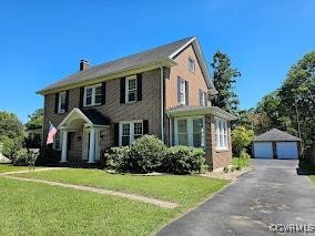 view of front of property featuring a front lawn, a garage, and an outbuilding