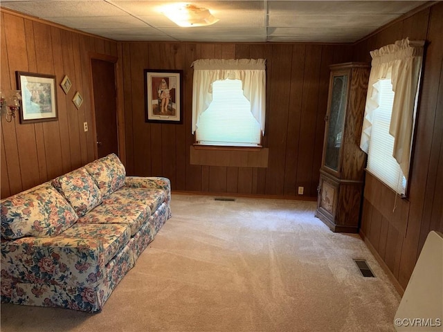 living room featuring wooden walls, light colored carpet, and visible vents