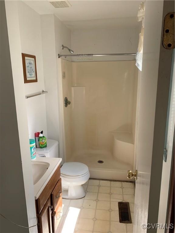 bathroom with visible vents, toilet, vanity, and walk in shower