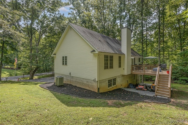 view of side of property featuring a lawn, a wooden deck, and central AC