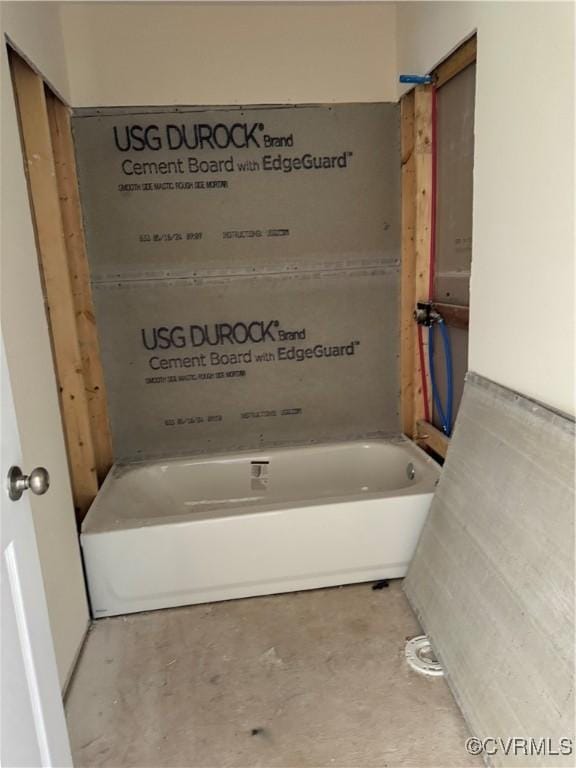 bathroom with a bathing tub and concrete flooring