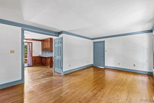 empty room with ornamental molding and light hardwood / wood-style flooring