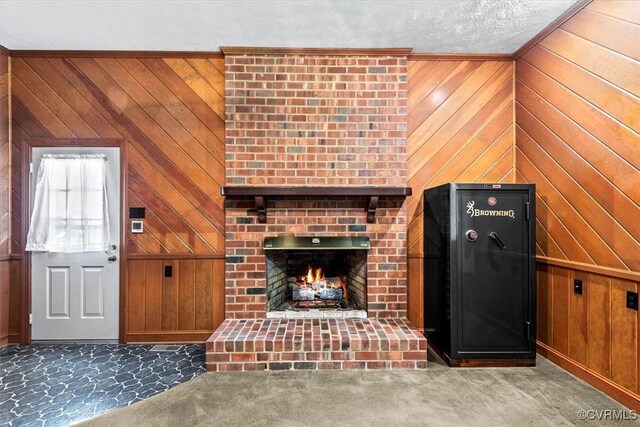 unfurnished living room featuring a textured ceiling, a brick fireplace, wood walls, and carpet