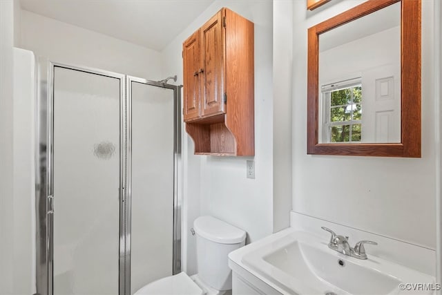 bathroom featuring a shower with door, vanity, and toilet