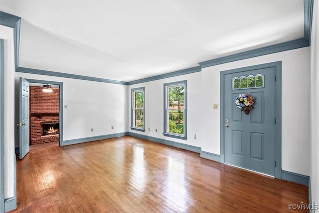 foyer entrance with ceiling fan, ornamental molding, hardwood / wood-style floors, and a fireplace