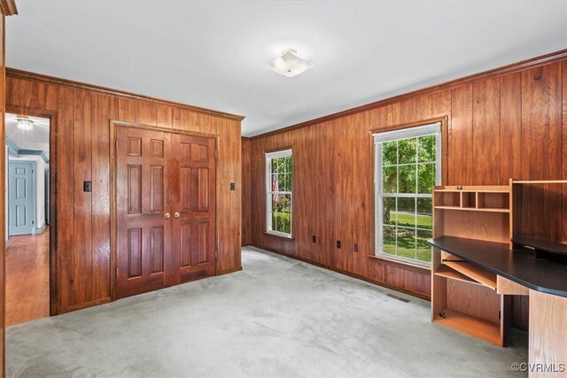 unfurnished office featuring wooden walls, crown molding, and light carpet