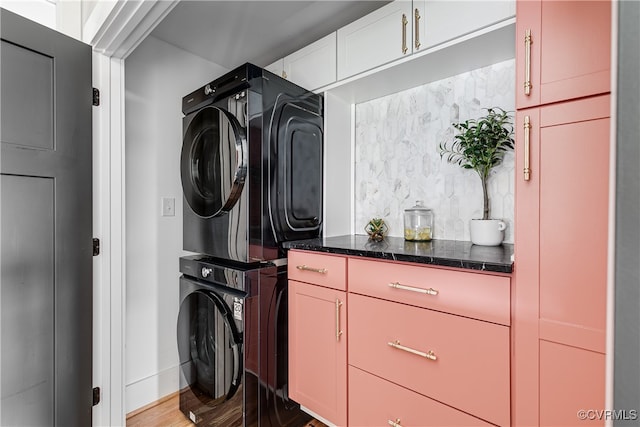 washroom featuring hardwood / wood-style flooring and stacked washer and dryer