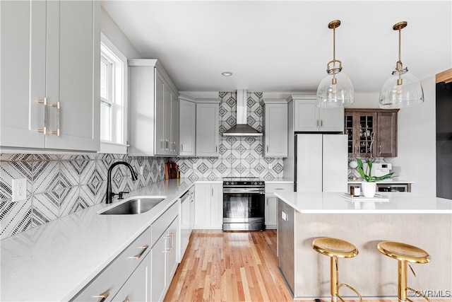 kitchen featuring tasteful backsplash, light hardwood / wood-style flooring, stainless steel appliances, sink, and wall chimney exhaust hood