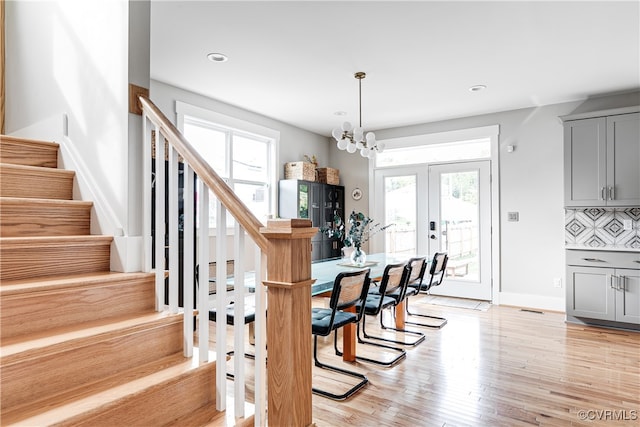 dining area with french doors, plenty of natural light, light hardwood / wood-style flooring, and an inviting chandelier