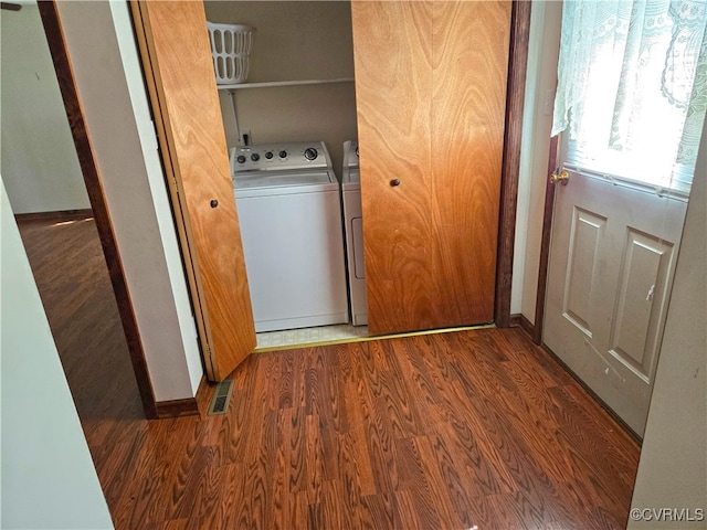 washroom with washing machine and clothes dryer and hardwood / wood-style flooring