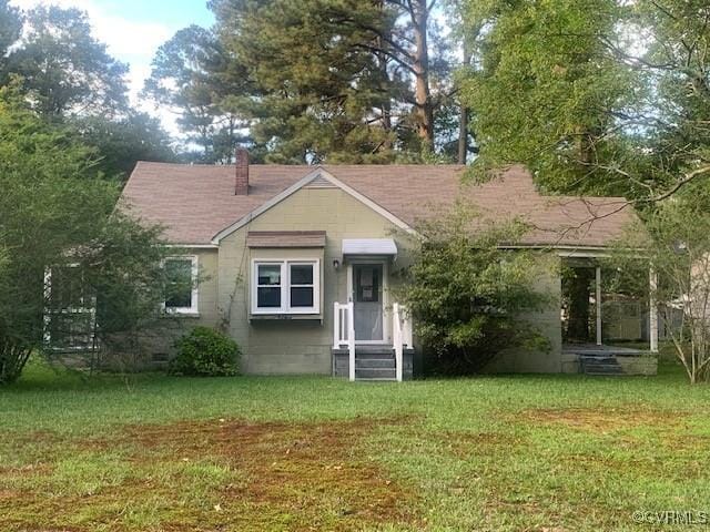 view of front of house featuring crawl space, a chimney, and a front yard