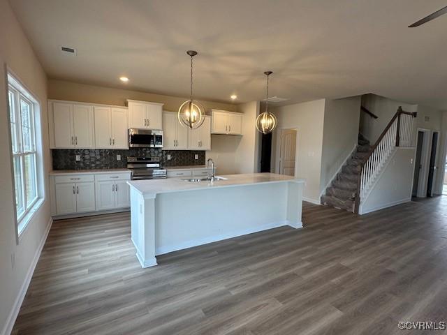 kitchen with appliances with stainless steel finishes, sink, a center island with sink, and white cabinets