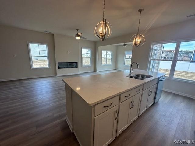 kitchen featuring sink, dishwasher, an island with sink, white cabinets, and decorative light fixtures